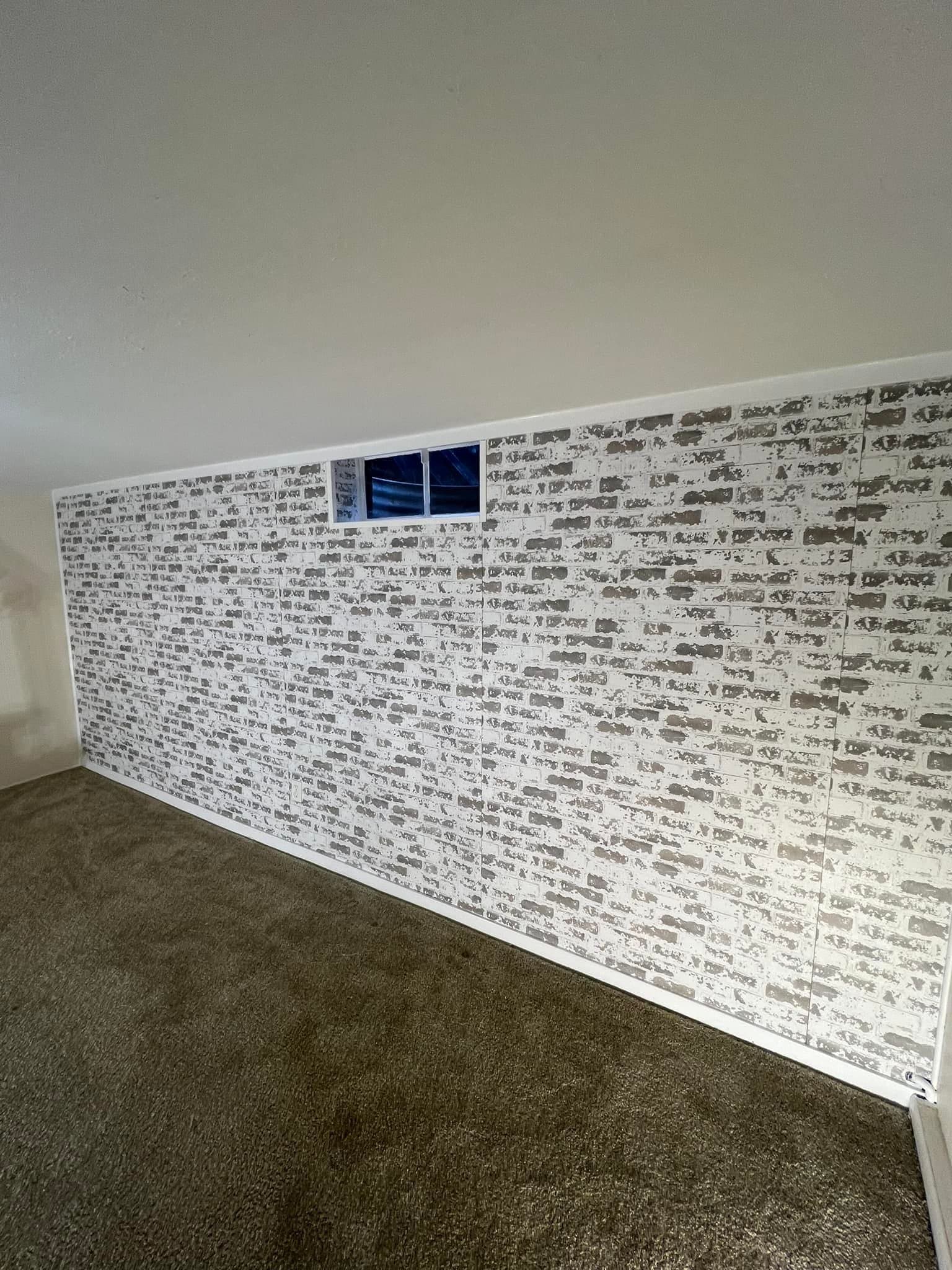 Basement room with a whitewashed brick feature wall and a high hopper window