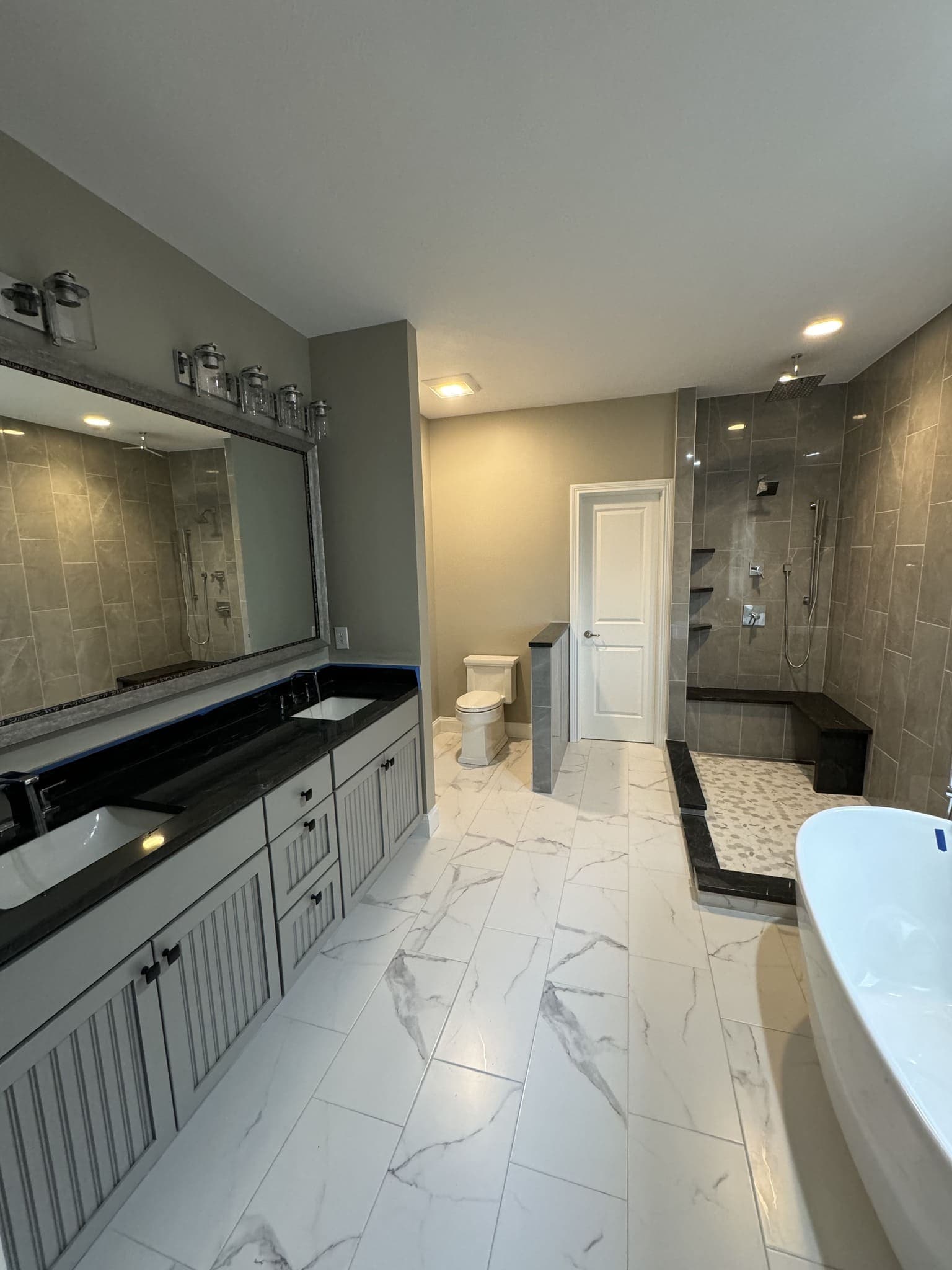 Bathroom with a double vanity, a tiled walk-in shower with a bench and a freestanding tub