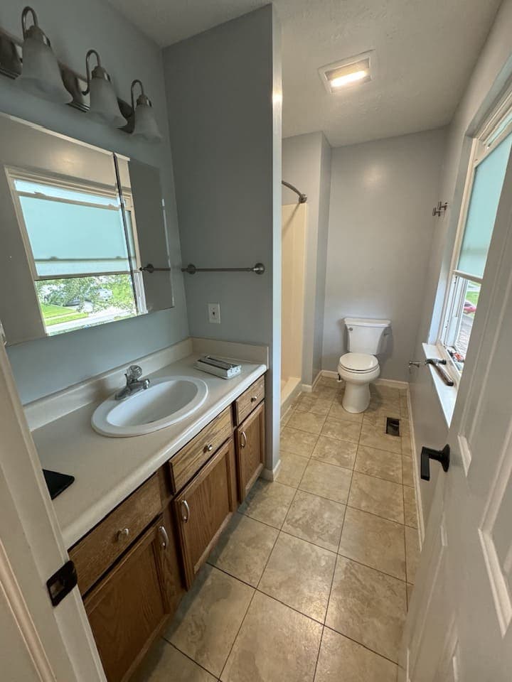 Bathroom with an oak vanity, tiled floor and a window over the sink