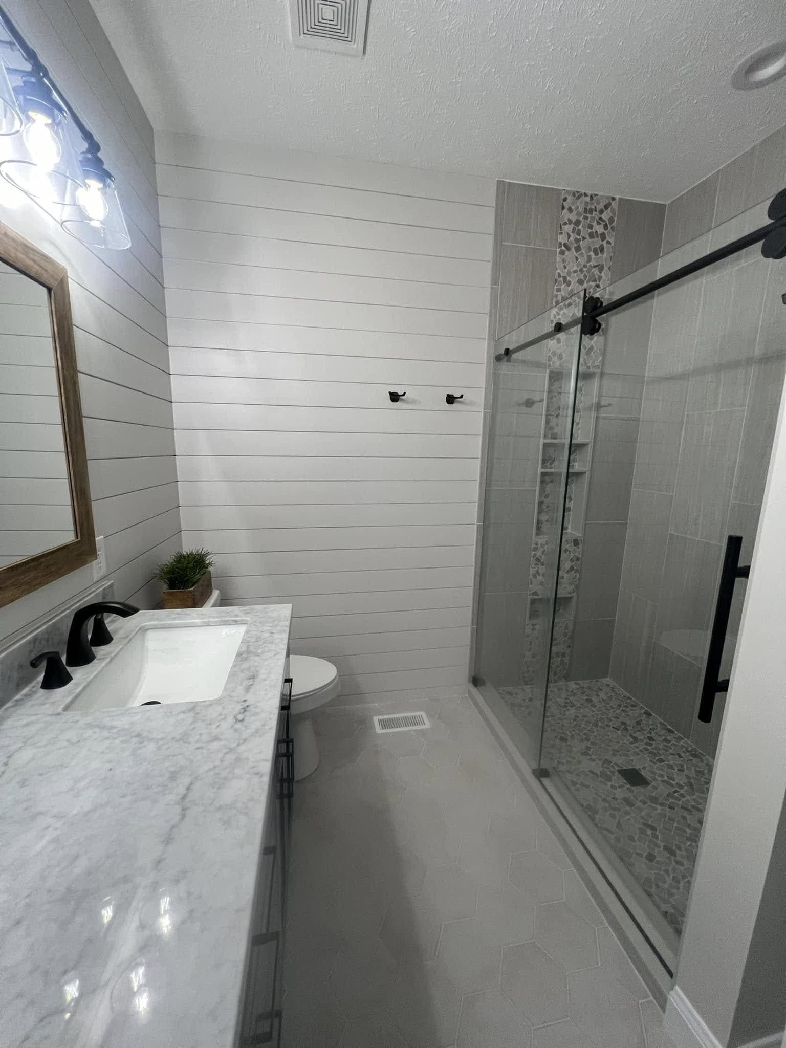 Bathroom with a shiplap wall, marble-look vanity and a sliding-glass shower