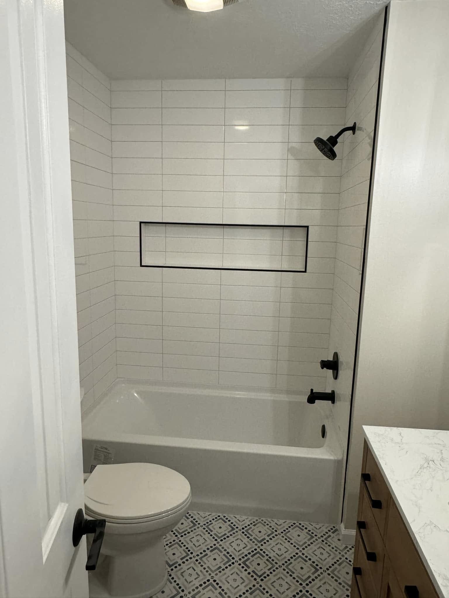 Bathroom with a white tiled tub surround, a full-width niche and patterned floor tile