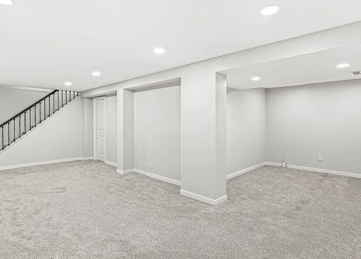 Finished basement with carpet, recessed lighting and a staircase with a black railing