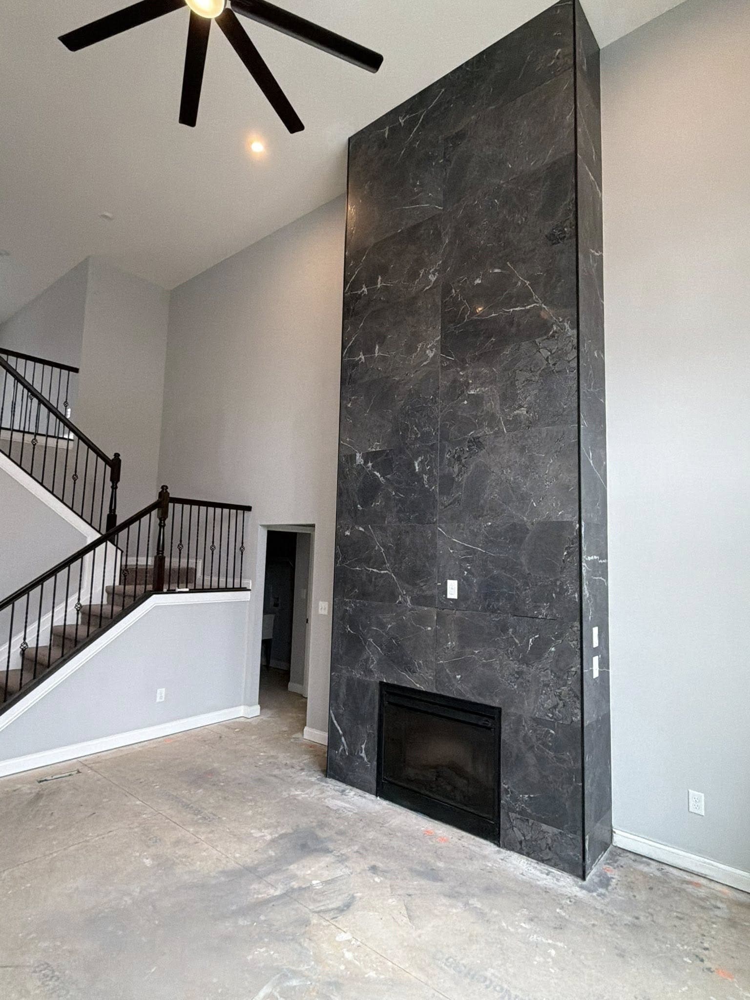 Floor-to-ceiling dark marble fireplace surround in a double-height living room