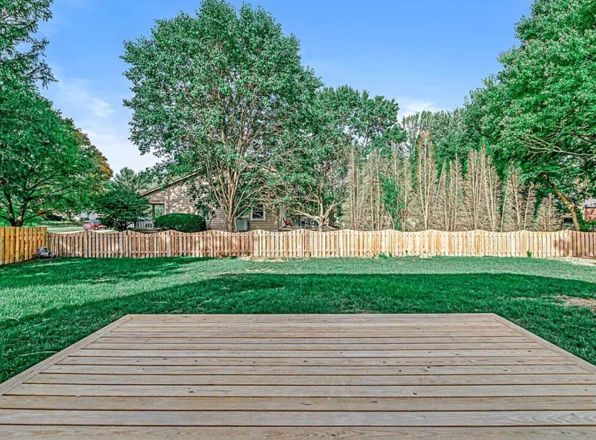 New wood deck and picket fence enclosing a back yard