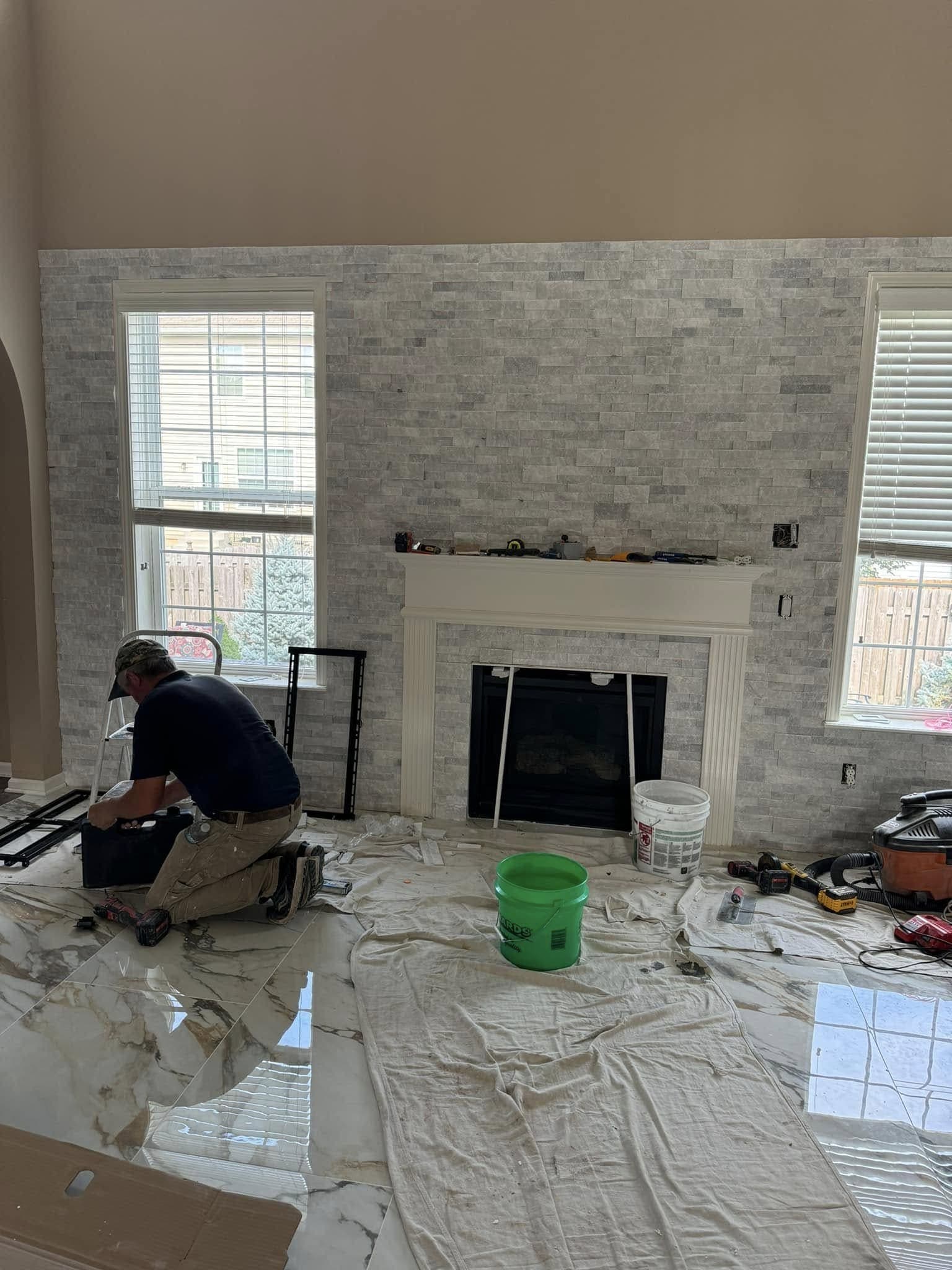 Whitewashed stacked-stone fireplace surround going up, with drop cloths over the floor